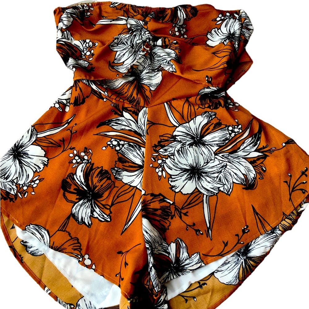 Strapless orange romper with floral pattern. Has an open back with a tie.